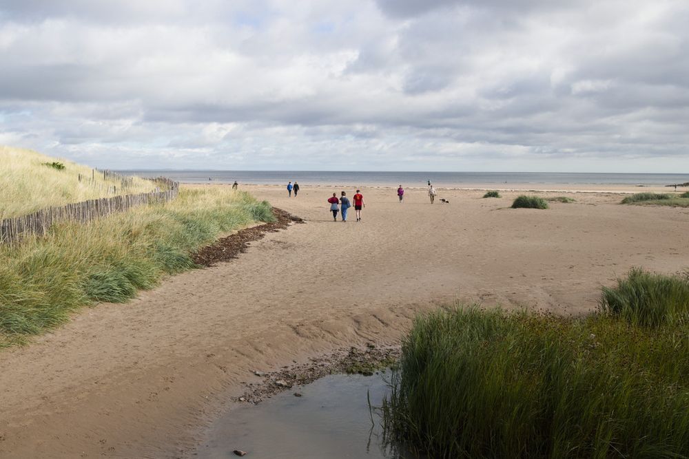 West Sands beach at St Andrews, Scotland, with the sea beyond the sand and people walking toward the water